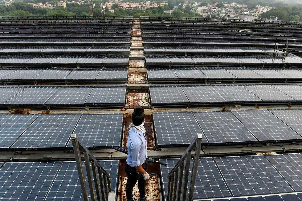 Indian PV deals: an employee watches in the distance as he stands among solar panels installed on the building of Indira Paryavaran Bhawan or the Indian Environment Ministry in New Delhi