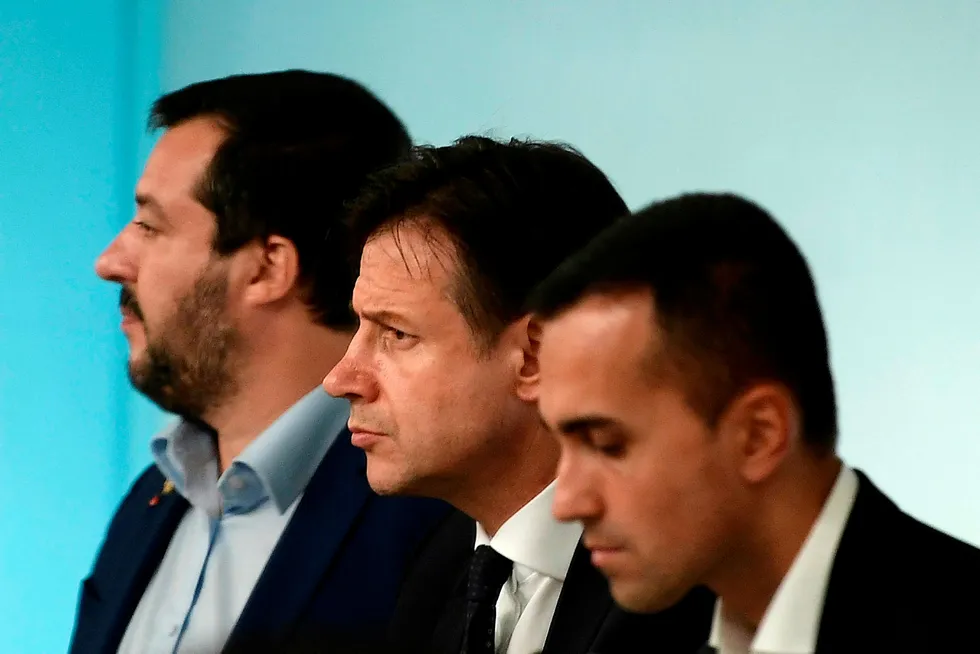 Italias nyvalgte statsminister, Giuseppe Conte, står mellom partilederne for de to regjeringspartiene. Til venstre står Matteo Salvini, leder for Ligaen. Til høyre står Luigi Di Maio, leder for Femstjernersbevegelsen. Vil trekløveret gi etter for presset fra Brussel?