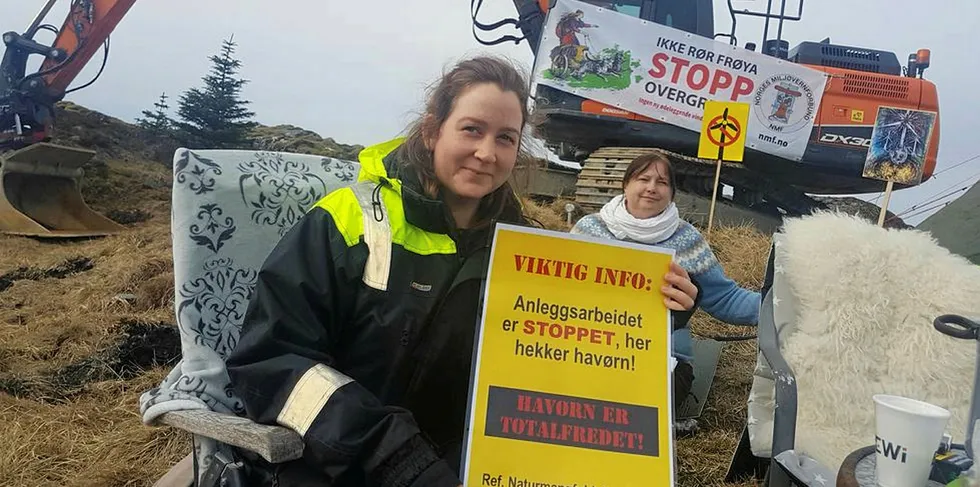 Pia Kjørsvik med plakaten som viser hvorfor de sitter foran gravemaskina.