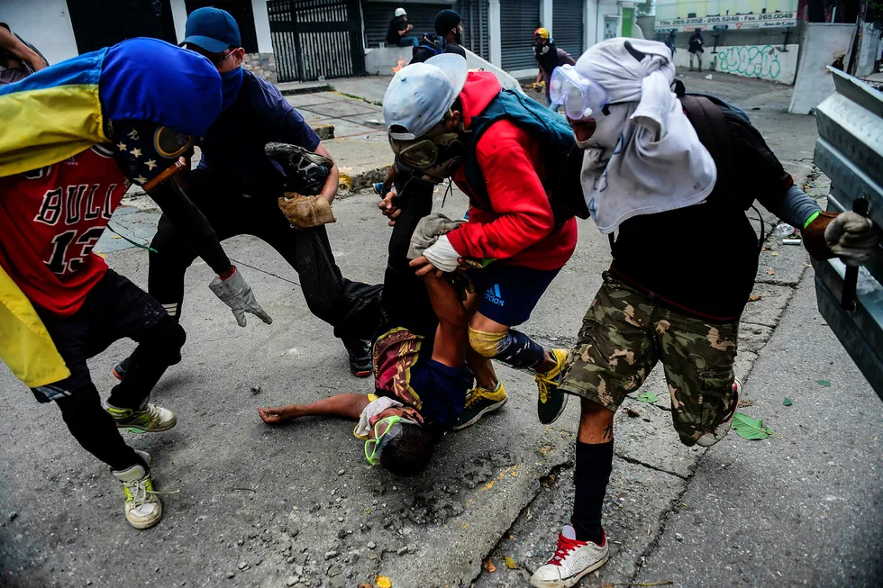 Opposisjonelle demonstranter forsøker å hjelpe en skadet venn etter sammenstøt med politiet. Foto: Ronaldo Schemidt/AFP photo/NTB scanpix
