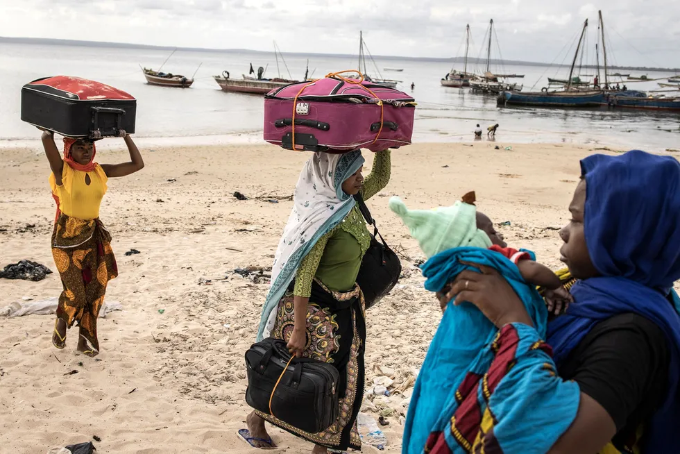 Exodus: women carry belongings off a boat as they arrive at Paquitequete beach in Pemba last month, after fleeing Palma