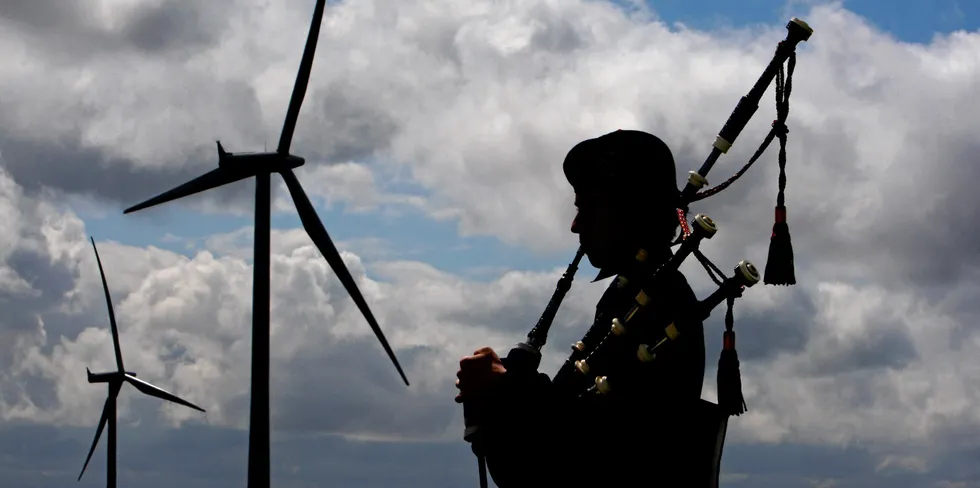 A bagpiper at Whitelee wind farm in Scotland.