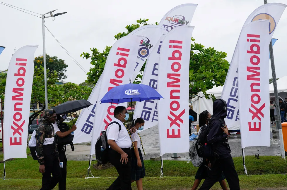 High school students walk past ExxonMobil banners at a job fair at the University of Guyana in Georgetown, Guyana.