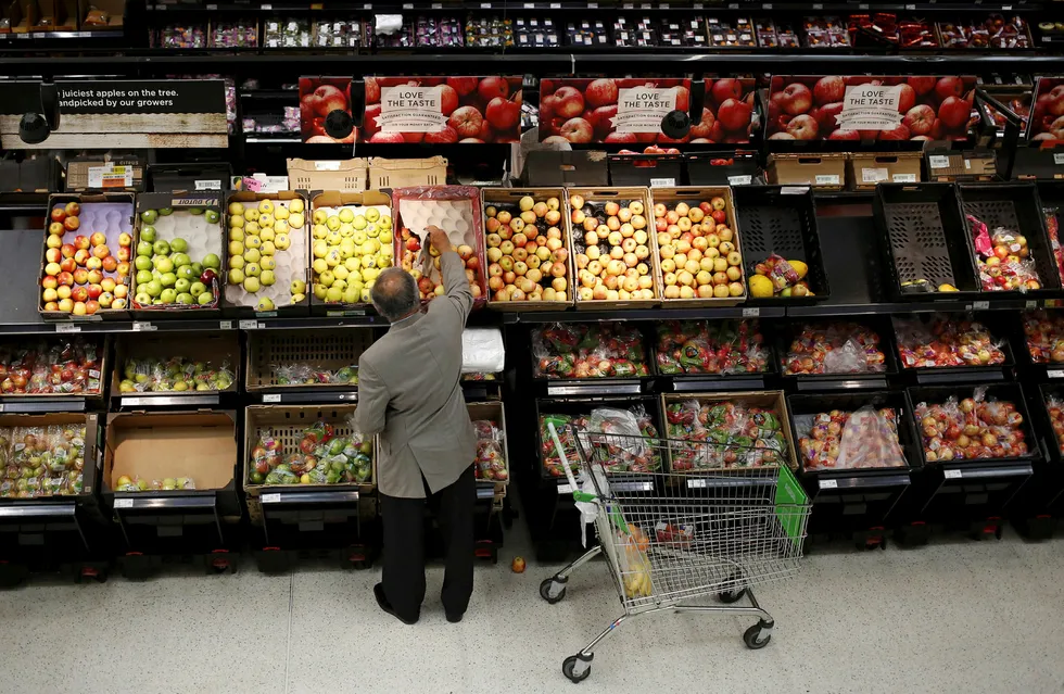 En mann velger epler i en Asda-butikk nordvest i London. Den WalMart-eide kjeden kan nå bli fusjonert med Sainsbury's. Foto: SUZANNE PLUNKETT