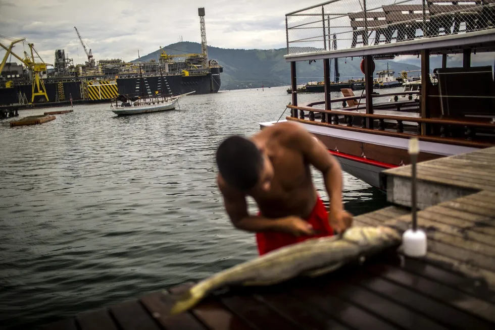 En fisker renser fisk ved anlegget til Petrobas i Angra Dos Reis, Brasil. Oljeselskapet Petrobas er et av selskapene Oljefondet har investert i. Det er Etikkrådet som vurderer om investeringer av Oljefondet er i strid med de etiske retningslinjene. Foto: Dado Galdieri/Bloomberg