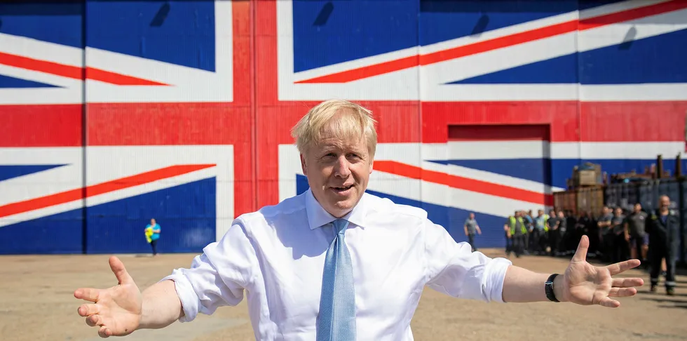 Conservative party leadership contender Boris Johnson poses for a photograph in front of a Union Jack on a wall at the Wight Shipyard Company at Venture Quay during a visit to the Isle of Wight on June 27, 2019.