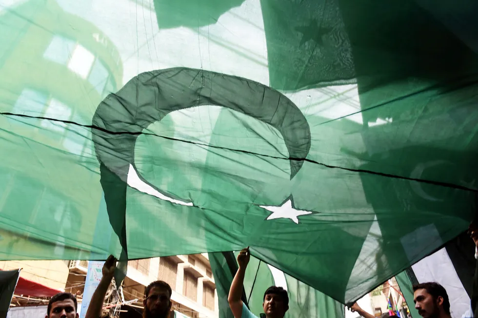 Flag day: Pakistani men hold their national flag in an Independence Day celebration