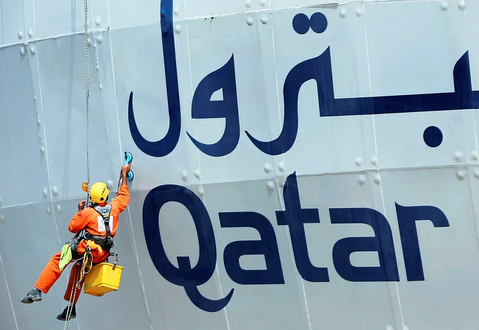 Reading the signs: a worker cleans the exterior of the Qatar Petroleum building in Doha