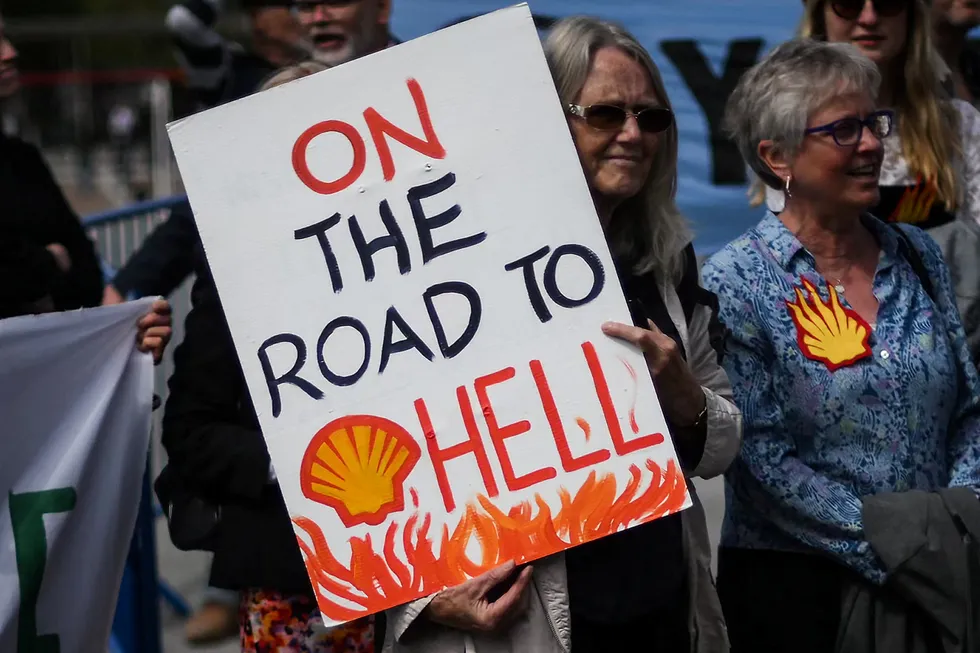 Burning issue: A member of the Dutch activist group Milieudefensie holds a placard while demonstrating outside ExCeL, in London, during Shell’s Annual General Meeting on Tuesday.
