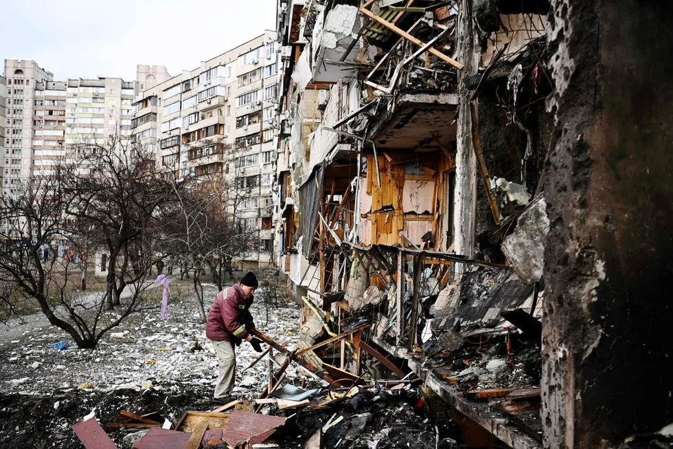 En mann rydder i debris fredag etter at russiske raketter traff et boligkompleks i en forstad til Kyiv.