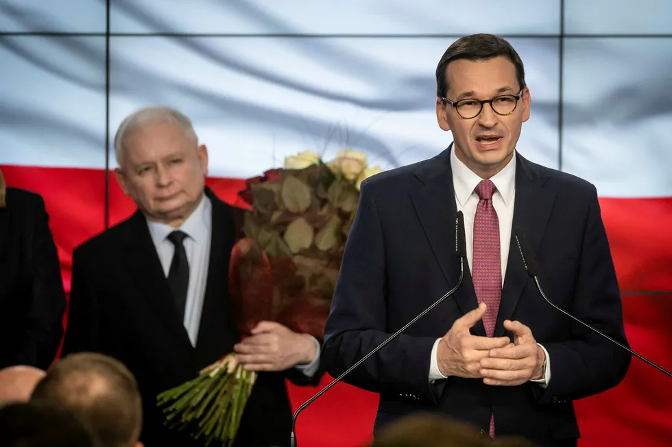 Polens statsminister Mateusz Morawiecki holder tale etter at resultatene fra valgdagsmålingen ble klare søndag 13. oktober. Partileder i Lov- og rettferdighetspartiet (PiS) Jaroslaw Kaczynski ser på i bakgrunnen.