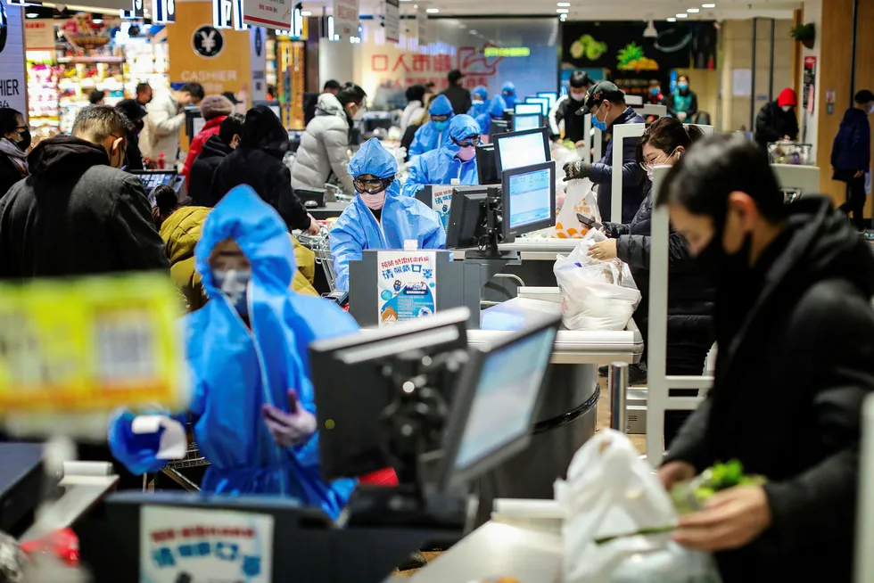 Kassabetjeningen i dette supermarkedet i Shenyang nord i Kina har byttet ut arbeidsuniformene med beskyttelsesdrakter, Alle kundene går også med munnbind i et forsøk på å beskytte seg selv og andre mot koronaviruset. Foto: STR/AFP/NTB Scanpix