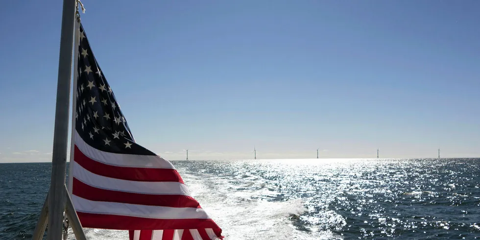 A US flag flies off the back of a ferry in front of the Block Island wind farm, off Rhode Island