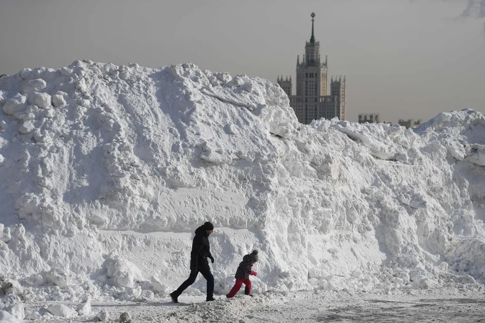 Transit fall: people walk past a pile of snow collected near the Red Square in the Russian capital of Moscow on 20 February 2021 after heavy snowfalls