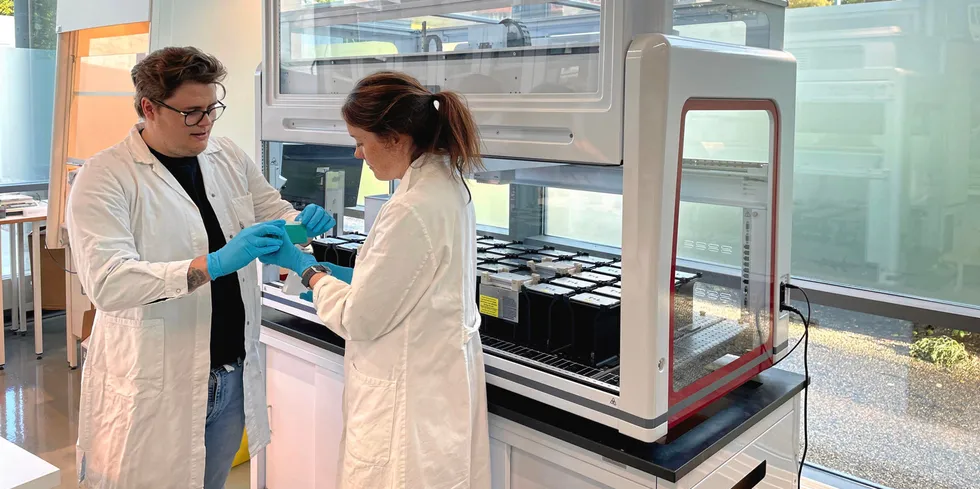 Preben Sangolt og Sigrid Rørvik foran en av robotene som renser DNA fra fiskevev i laboratoriet hos Blue Analytics.