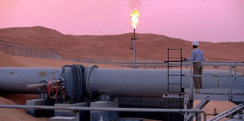 SHAYBAH, SAUDI ARABIA - MARCH 2003: A worker stands at a pipeline, watching a flare stack at the Saudi Aramco oil field complex facilities at Shaybah in the Rub' al Khali ("empty quarter") desert on March 2003 in Shaybah, Saudi Arabia. (Photo by Reza/Getty Images) . Saudi pipeline.