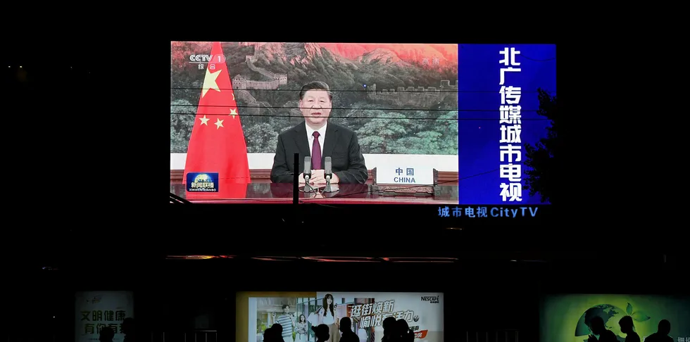 An image of Chinese President Xi Jinping appearing by video link at the United Nations 75th anniversary is seen on an outdoor screen as pedestrians walk past below in Beijing.