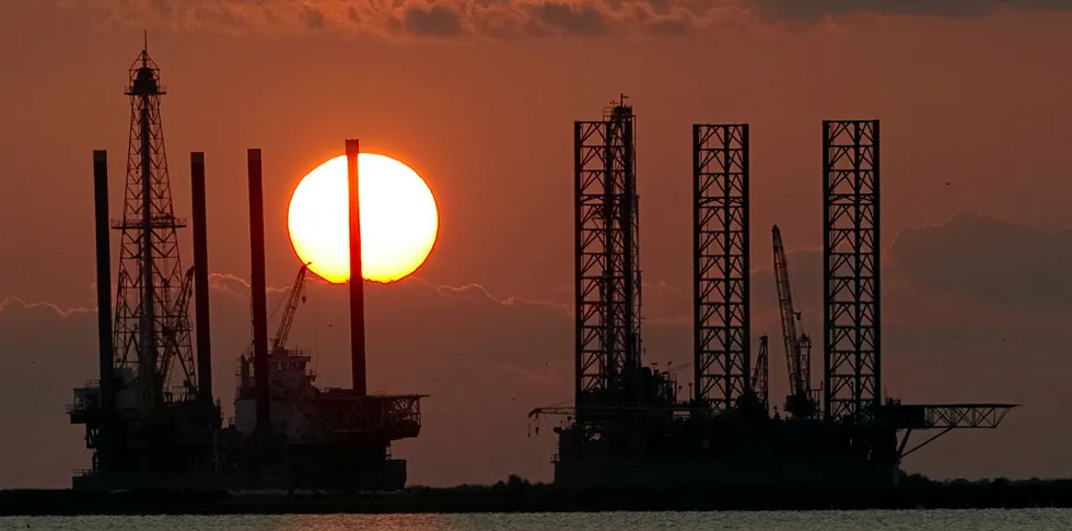 Sun setting behind two under construction offshore oil platform rigs in Port Fourchon, Louisiana, during clean-up of the BP Deepwater Horizon oil spill in 2010