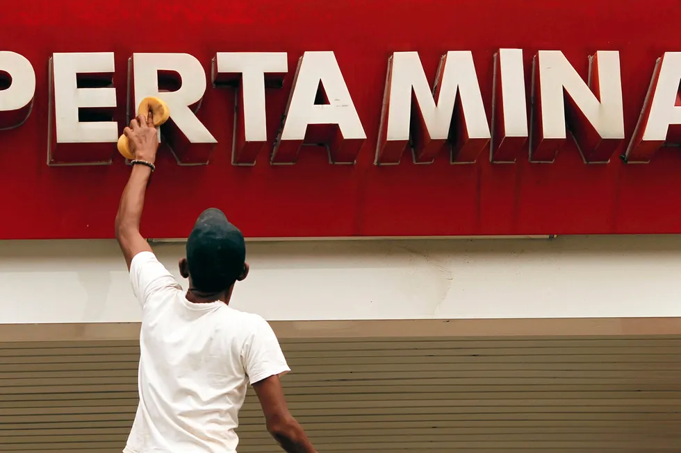 Logo: a worker cleans a sign of Indonesian state oil company Pertamina at a petrol station in Bekasi, in Indonesia's West Java province.