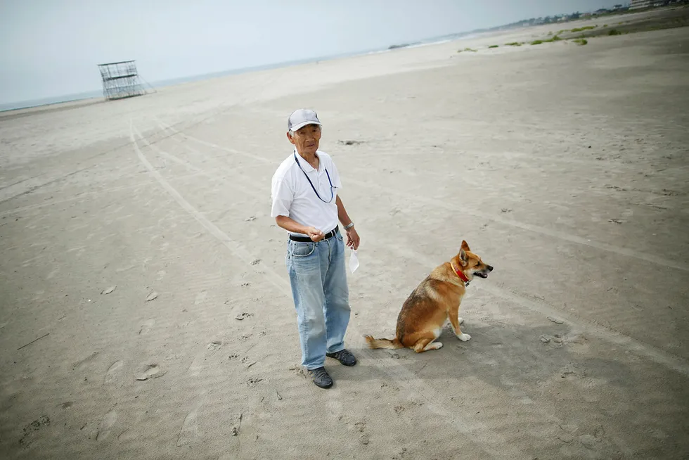 Forskere har målt høye nivåer av radioaktiv stråling på strender langt fra det ødelagte kjernekraftverket i Fukushima. På bildet ser vi lokal beboer Takeshi Takaki ( 71) og hans hund Marron på den tomme stranden Yotsukura 40 kilometer fra Fukushima. Denne stranden er ikke undersøkt av forskerne. Foto: Issei Kato/Reuters/NTB scanpix