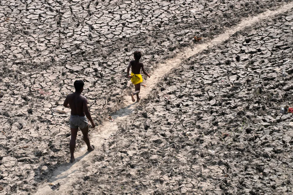 En mann og en gutt går på den inntørkede elven Yamuna, etter ekstremt varmt vær i den indiske hovedstaden New Delhi. En usedvanlig tidlig og brutal hetebølge har ført til akutt mangel på elektrisitet, fordi millioner av mennesker forsøker å kjøle seg ned.