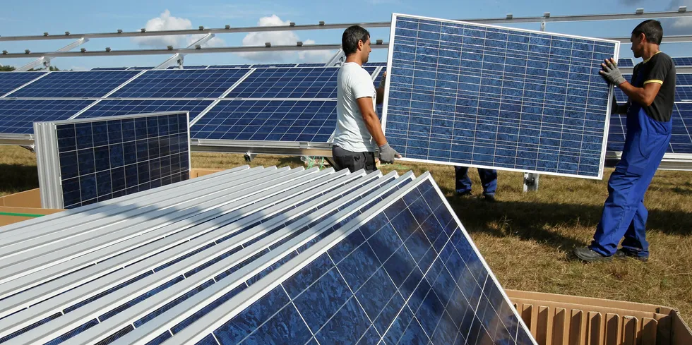 Workers install solar panels atSolarpark Eggersdorf near Muencheberg, Germany