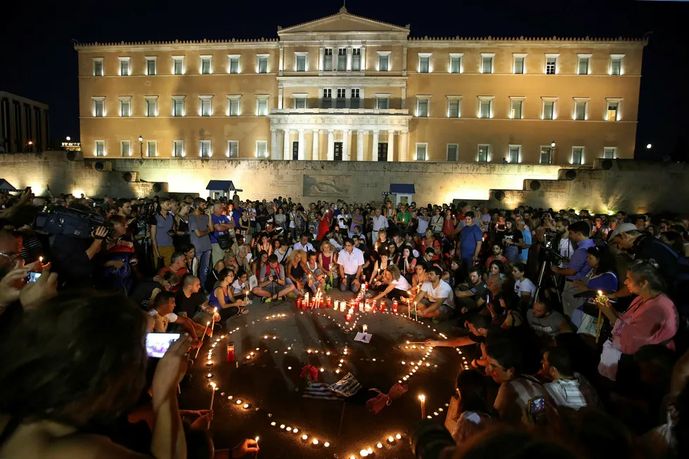 Omkring 500 mennesker var samlet utenfor den greske nasjonalforsamlingen mandag kveld. De la ned blomster og tente lys til minne om ofrene for landets dødeligste skogbrann på mange tiår. Foto: Thanassis Stavrakis / AP / NTB Scanpix