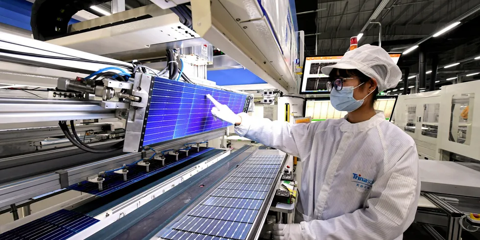 An employee works on the production line of solar panels at a factory of Trina Solar.