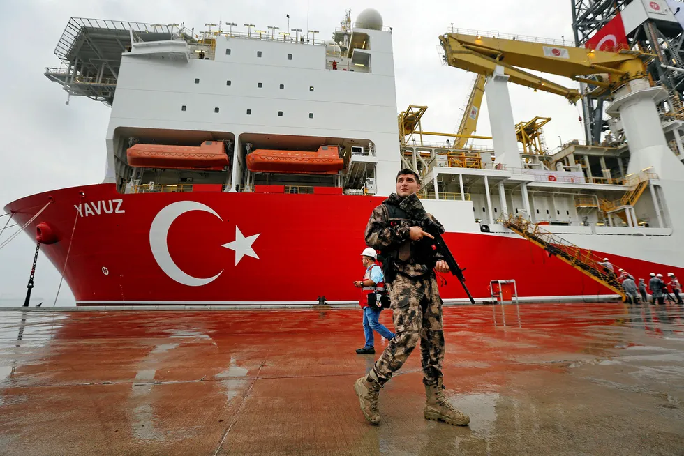Exploration efforts: Turkish police officer patrols the dock, backdropped by drillship Yavuz