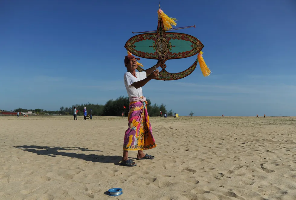 Taking flight: kitemaker Shafie Jusoh checking the prevailing wind directions before launching a traditional wau bulan kite at Pantai Geting beach in Peninsular Malaysia's Kelantan state