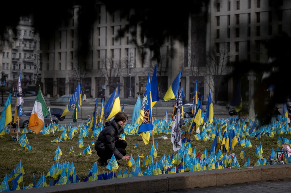 En kvinne setter ned flagg ved et minnesmerke for falne ukrainske soldater i Kyiv.