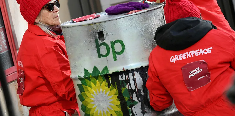 Greenpeace activists sit chained into oil barrels as they protest outside the headquarters of oil giant BP in London on February 5, 2020, on the day that the company's new was set to take up his role.