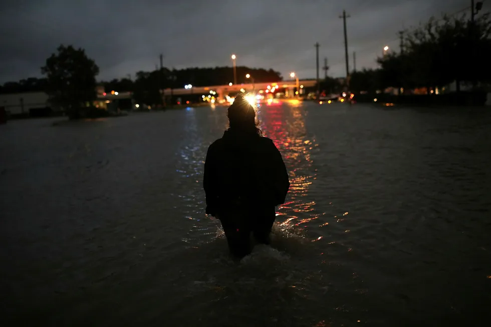 En person vasser med vann til hoftene gjennom natten i Houston, en av svært mange som må evakuere etter at orkanen Harvey traff land fredag. Nå stiger dødstallene. Foto: WIN MCNAMEE