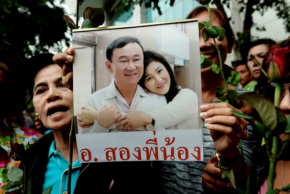 Bildet, som ble tatt i august, viser en kvinne som holder opp et bilde av Thailands tidligere statsminister Yingluck Shinawatra og broren Thaksin Shinawatra. Foto: Lillian Suwanrumpha/AFP/NTB scanpix