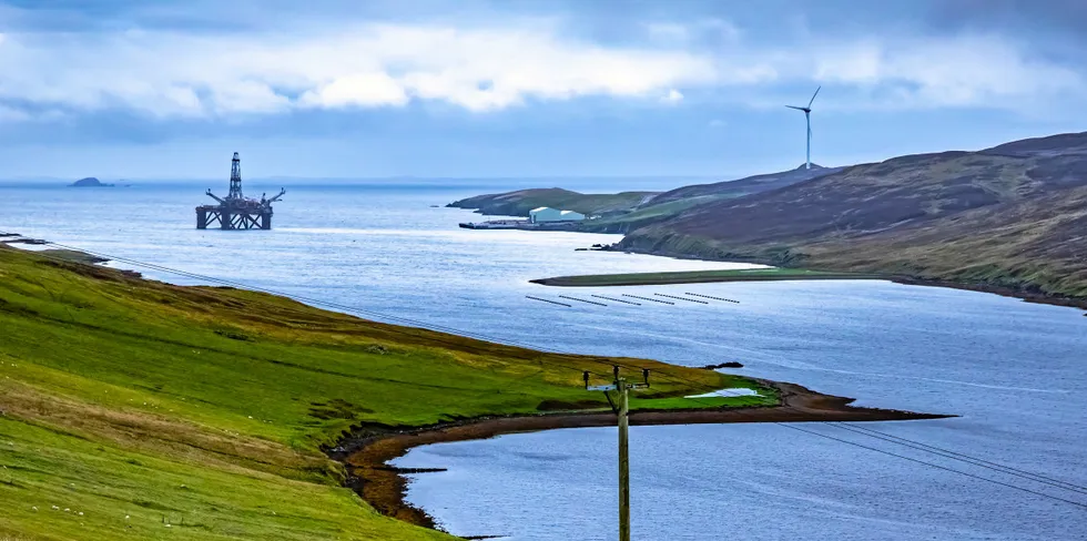 An oil platform and a wind turbine seen from Shetland.