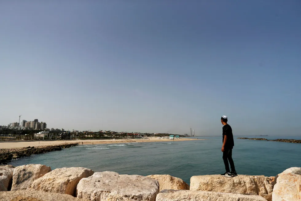 Deal: a boy looks at the Mediterranean Sea as he stands on rocks at the beach in the southern Israeli city of Ashkelon