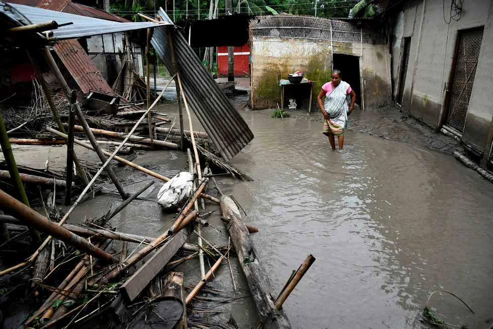 An Indian woman searches her belongings near the debris of her house following floodwaters in Kasuarbori village, in the Indias northeastern state of Assam, on July 13, 2019. - At least 17 people have been killed across Nepal after torrential monsoon rains induced floods and landslides, officials said on July 12. (Photo by Biju BORO / AFP)