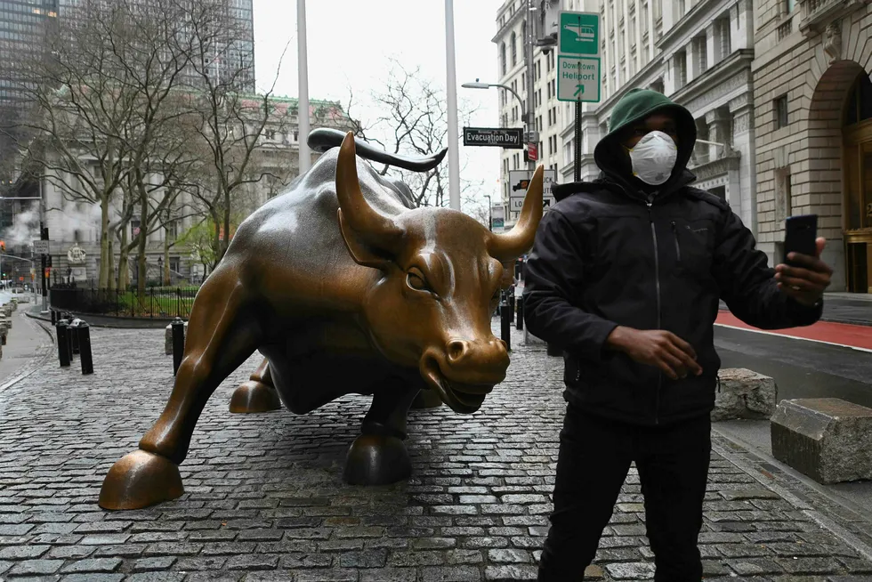 En mann med munnbunn tar en selfie foran den kjente oksen nær New Stock Exchange tidligere i mars.