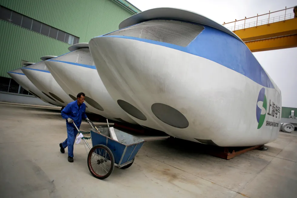 Vessel deal: an employee pushes a cleaning cart next to a wind turbine outside an assembly workshop at Shanghai Electric