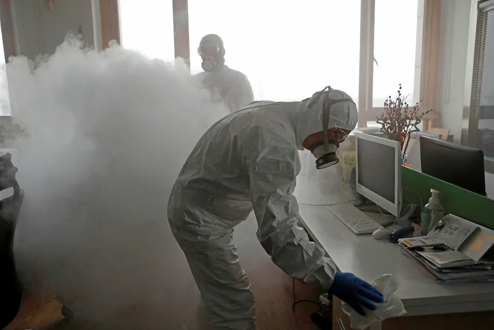 Precautions: Workers with sanitising equipment disinfect an office following a suspected outbreak of the coronavirus