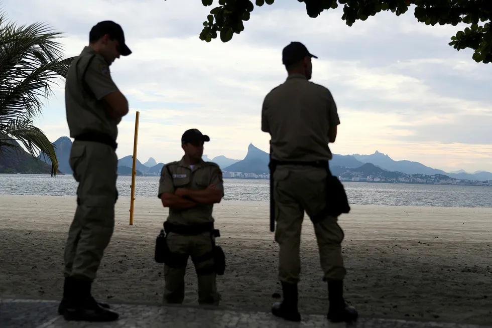 Lokalt politiet patruljerer stranden Icarai ved Sukkertoppen i Brasil torsdag. Landet innfører enda strengere regler nå. Foto: Silvia Izquierdo