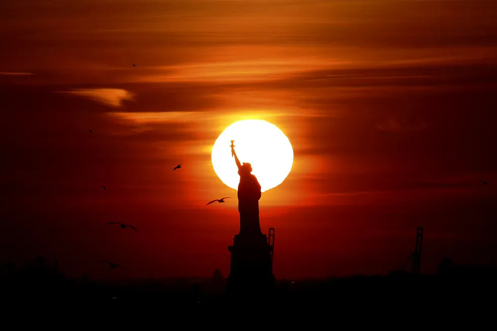 Solnedgang bak Frihetsgudinnen i New York. En varm måned kan ha bidratt til å løfte jobbtallene. Foto: Reuters