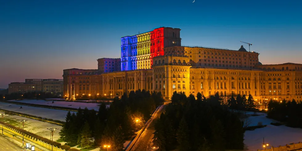 Palace of the Parliament building in Bucharest with the national flag of Romania projected on it .