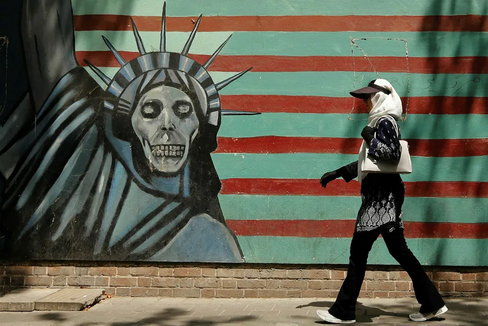 En iransk kvinne går forbi en grafitti tegnet på den tidligere amerikanske ambassaden i Tehran. USAs president Donald Trump har nettop gjeninnført sanksjonene mot Iran som ble lettet i 2015.