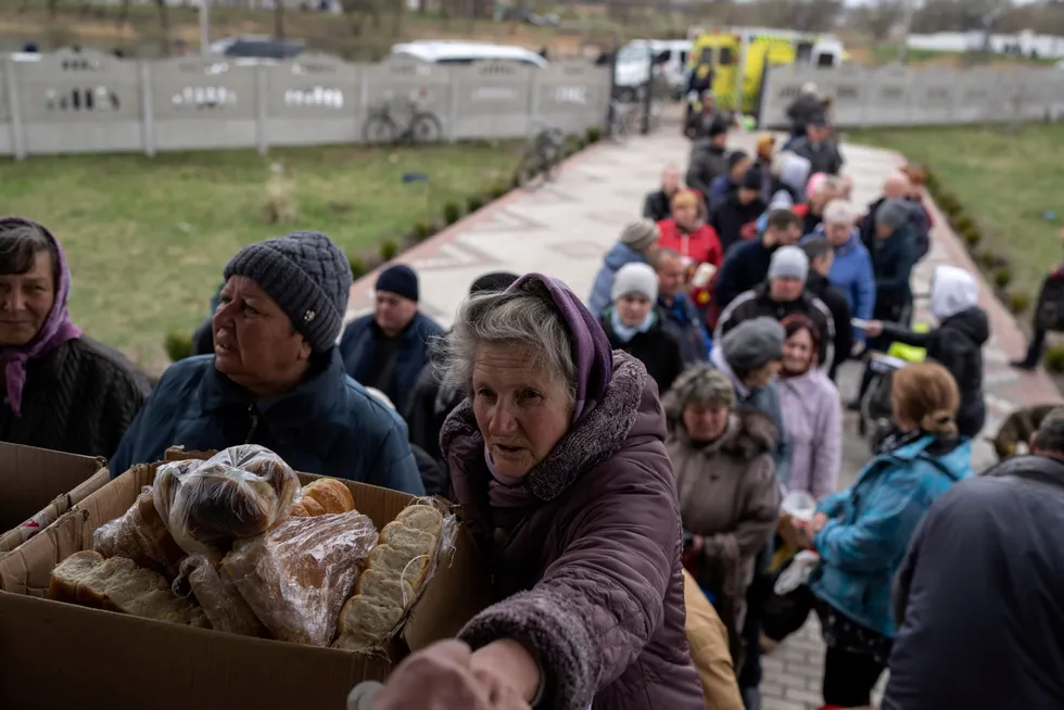 Ukrainske innbyggere mottar moat fra en kirke i Borodyanka, nordvest for hovedstaden Kyiv på søndag. Verdensbanken spår en full kollaps av økonomien – med store ringvirkninger til hele regionen.