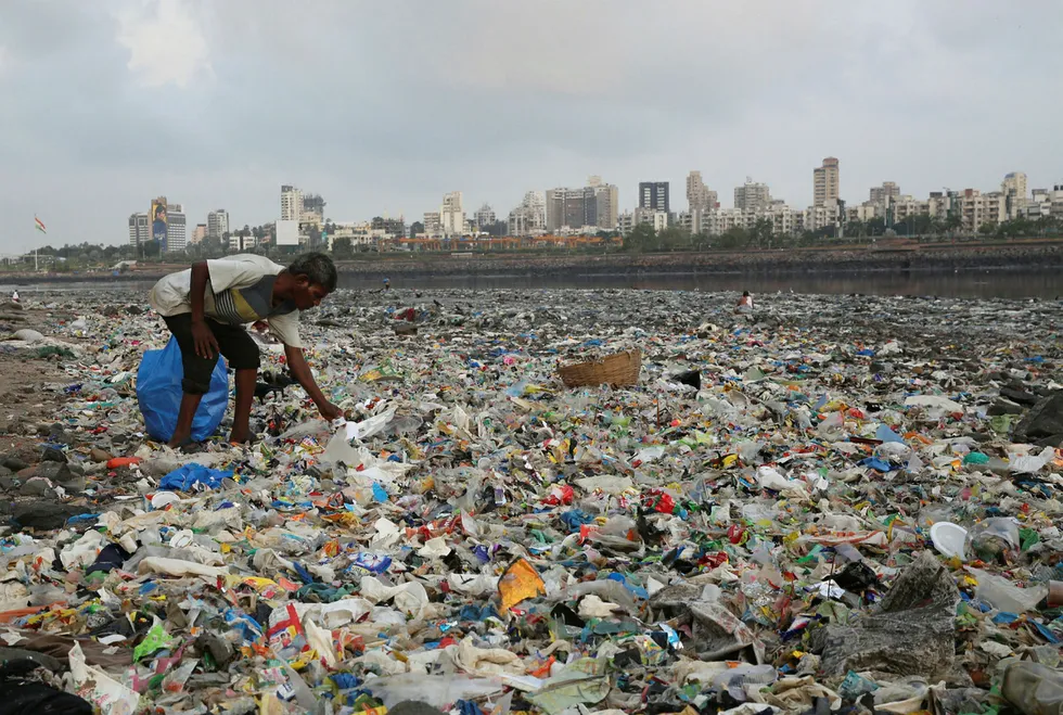 En mann samler inn plast og andre resirkulerbare materialer fra stranda langs Arabiahavet i Mumbai i India. Foto: Rafiq Maqbool/NTB Scanpix