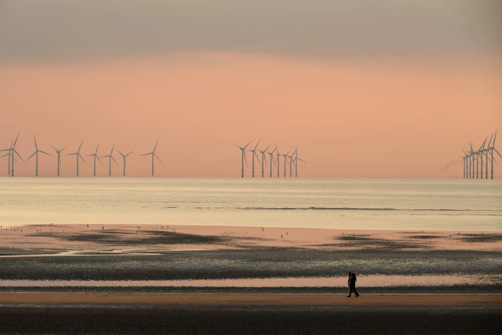 Transition path: people walking on the beach at New Brighton, north-west England, with the Burbo Bank wind farm on the Irish Sea in the background