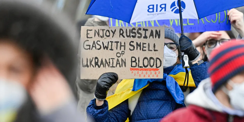 A demonstrator holds a placard reading "Enjoy Russian gas with smell of Ukrainian blood" during a protest against Russia's invasion in front of the Chancellery in Berlin.