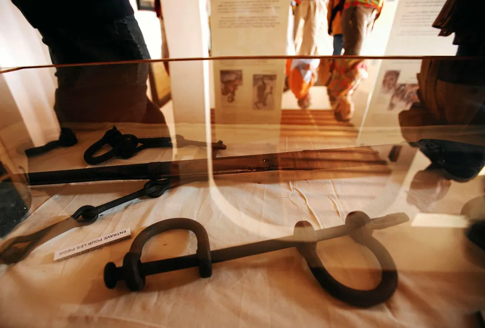 Visitors are reflected in a glass display case containing iron leg shackles at the House of Slaves museum on Goree Island near Senegal's capital Dakar