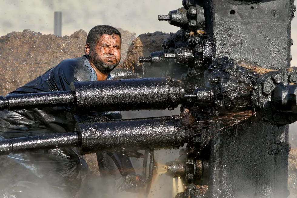 IEA oppjusterer estimatene for både etterspørsel og tilbud neste år. Avbildet er en irakisk oljearbeider som prøver å reparere en pumpe på en oljebrønn i Bob Al-Sham, Irak.